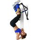 Model using blue and black inversion rack system for inverted exercises, wearing blue shorts and black leg straps on white ba