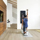 Man in blue tank top and black shorts using lululemon Studio Mirror Pro on white wall in home gym space
