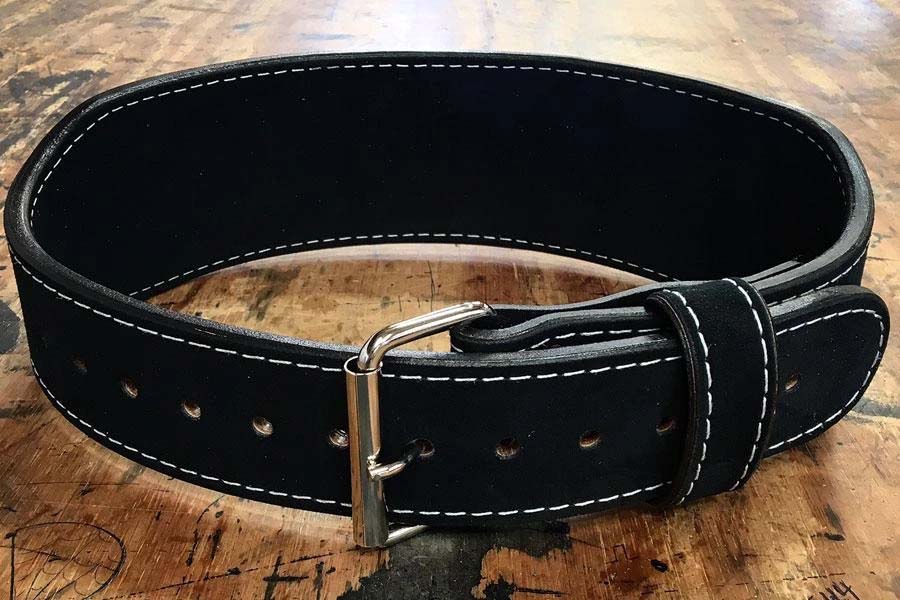 Black leather weightlifting belt with white stitching, metal buckle, and rivets, displayed flat on wooden surface
