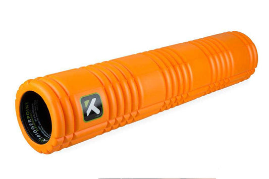 Bright orange cylindrical foam roller with deep groove patterns and black branded logo patch on side, displayed on white back