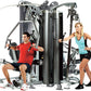 Multi-station gym equipment with gray and black frame featuring three workout stations, demonstrated by man in red shirt seat