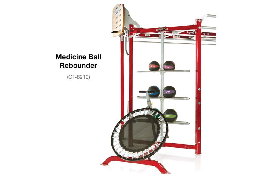 TuffStuff Medicine Ball Rebounder with red frame, circular rebound surface, storage shelves holding colored medicine balls, a