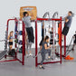 Red metal multi-station fitness training system with various exercise attachments, multiple people using different stations s