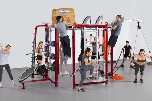 Red metal multi-station fitness training system with various exercise attachments, multiple people using different stations s