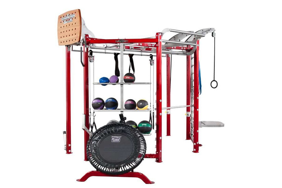 Red multi-station fitness training system with black trampoline, medicine ball storage shelves, wooden pegboard, chin-up bar,