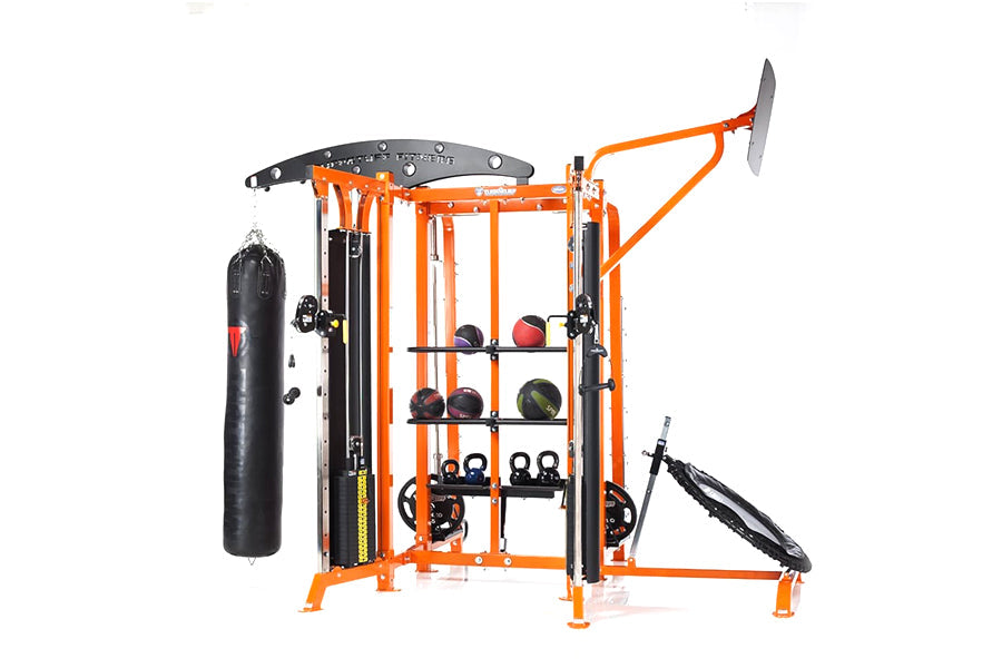 Multi-station home gym with orange metal frame, black weight plates, medicine balls, punching bag, and cable machine attachme