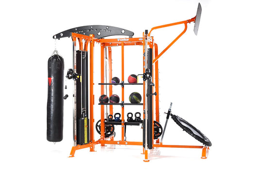 Orange and black multi-station home gym with heavy bag, medicine balls on shelves, lat pulldown, and leg press attachments on