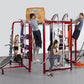 Red metal multi-station training rig with multiple users performing various exercises including pull-ups, step-ups, and rope 