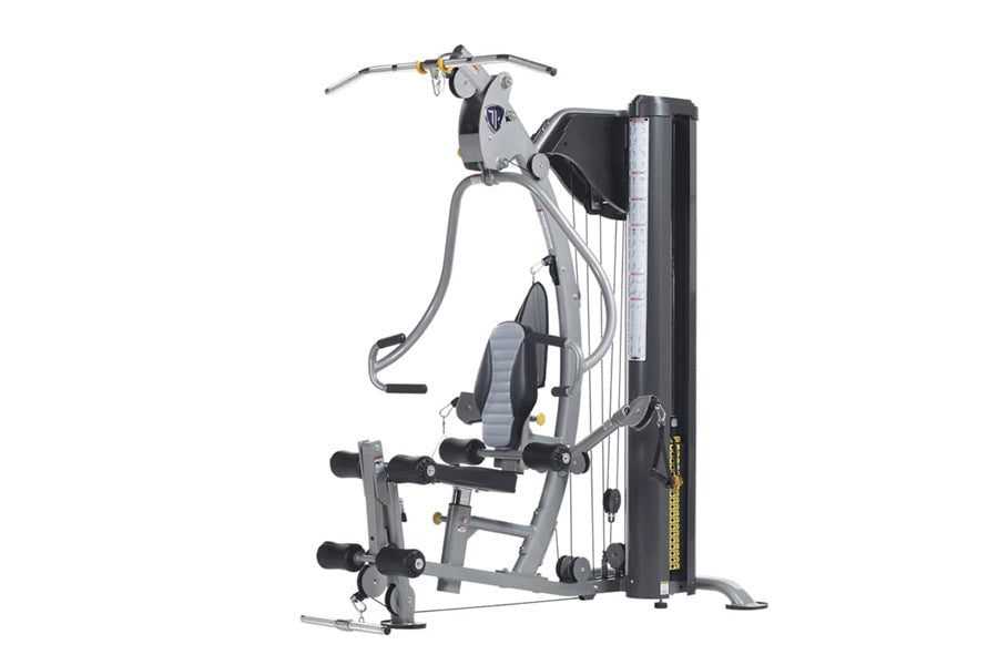 TuffStuff Classic home gym with silver frame, black seat, cable machine arms, and leg press attachment on white background