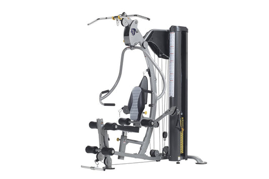TuffStuff Classic home gym with silver frame, black seat, cable machine arms, and leg press attachment on white background