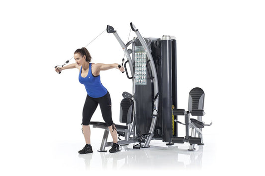 Woman using black and silver dual stack functional trainer with cable handles, demonstrating chest fly exercise on white back