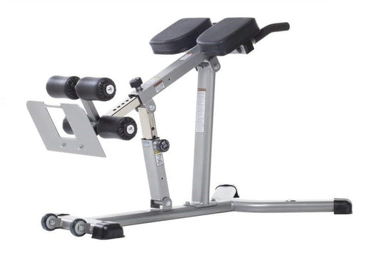 Gray adjustable hyper-extension bench with dual black leg extension pads, padded seat, and integrated dumbbell holders on whi
