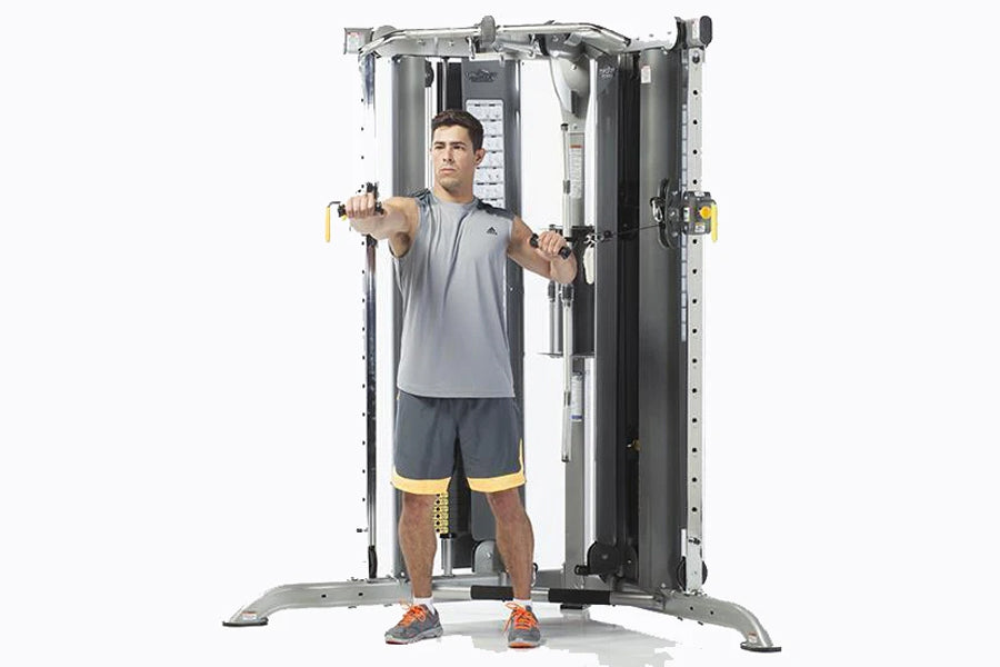 Man using dual-cable smith press machine with gray frame and black columns, wearing gray tank top and dark shorts with yellow