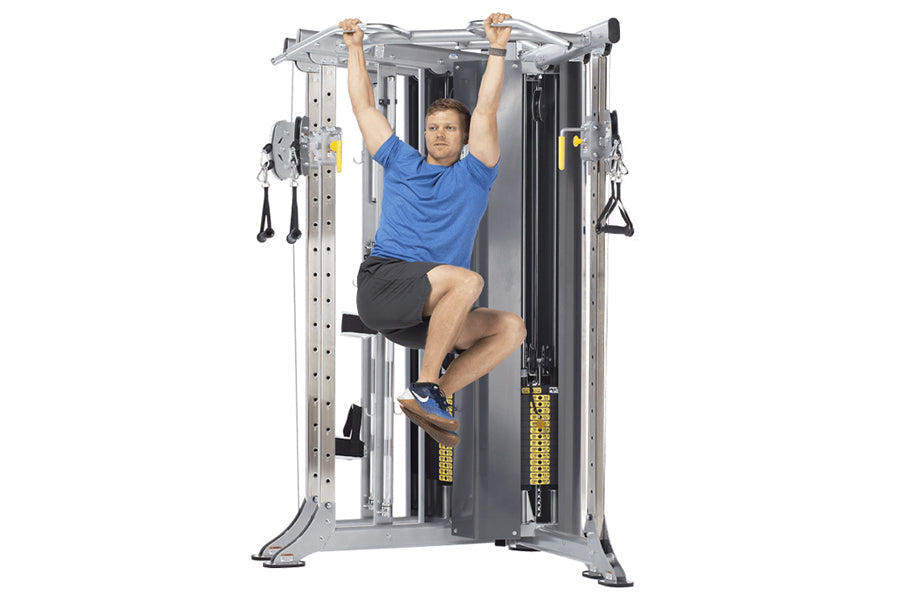 Man in blue shirt using silver and black dual adjustable pulley machine with yellow accents, demonstrating pull-up exercise o