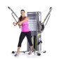 Woman wearing magenta tank top and black capris demonstrating TuffStuff Evolution dual stack functional trainer with arms ext