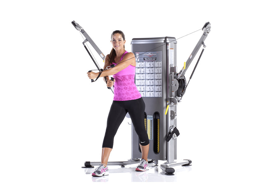 Woman wearing magenta tank top and black capris demonstrating TuffStuff Evolution dual stack functional trainer with arms ext