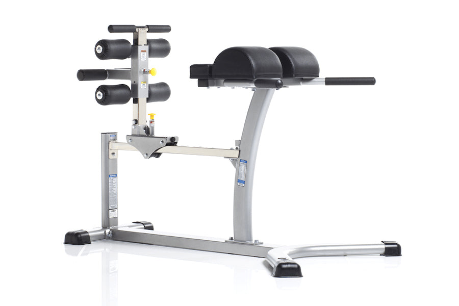 TuffStuff Evolution Glute/Ham Bench with gray metal frame, black padded seat and backrest, dumbbell rack on left side, and bl