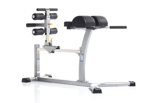 TuffStuff Evolution Glute/Ham Bench with gray metal frame, black padded seat and backrest, dumbbell rack on left side, and bl