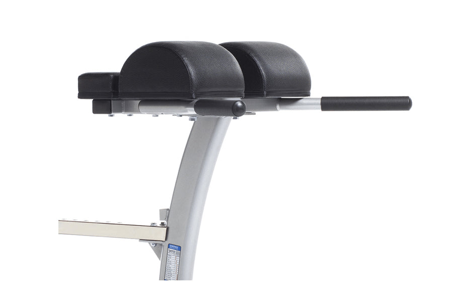 TuffStuff Evolution stationary exercise bench with black padded seat and leg extension attachment, gray steel frame on white 