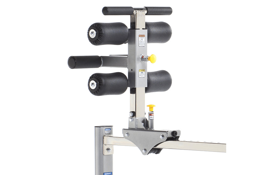 TuffStuff Evolution Glute/Ham Bench with gray steel frame, black padded roller attachments, and T-bar handlebar on white back