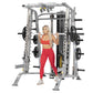 Silver and black Smith machine with weight plates, worn by model in red sports bra and leggings on white background