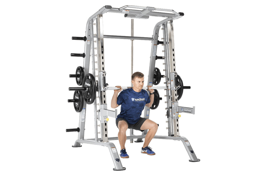 TuffStuff Evolution silver Smith machine with half cage combo, man in navy shirt performing squat with barbell, loaded weight