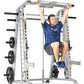 Man using silver TuffStuff Smith machine with black weight plates, performing pull-up exercise on horizontal bar