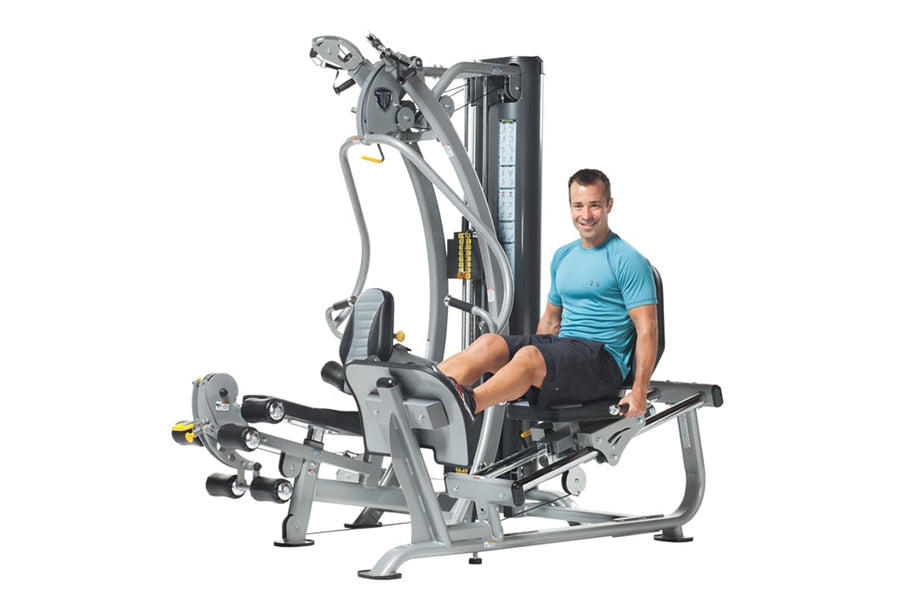 Male model in blue shirt using gray and black leg press machine with cable attachment on white background