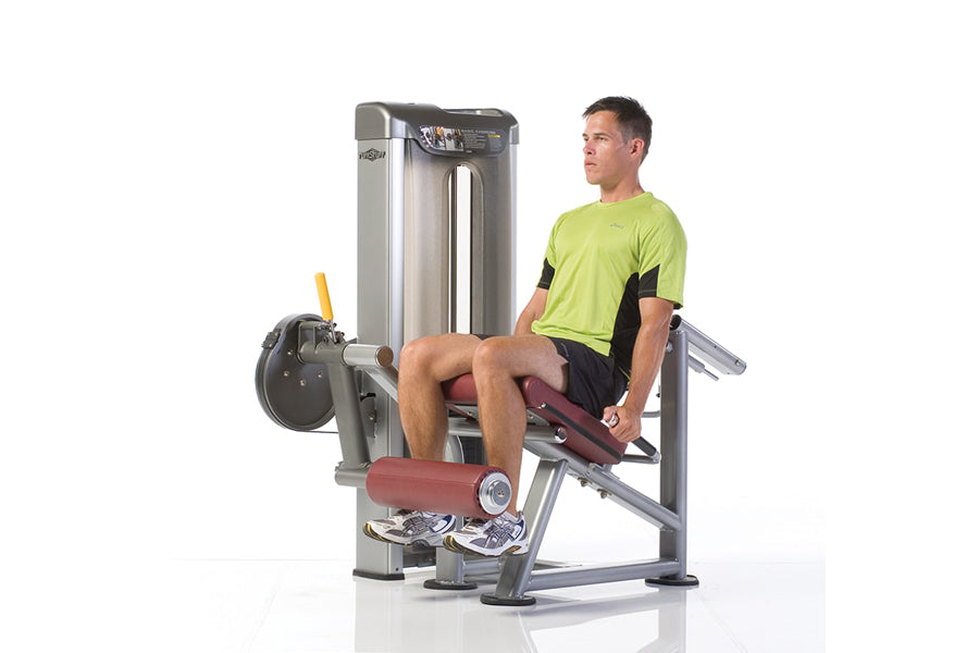 Man in lime green shirt using TuffStuff leg extension machine with silver frame and burgundy padding on white background