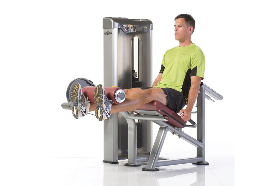 Man in lime green shirt using silver leg extension machine with burgundy seat and foot pads
