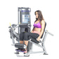 Woman in purple sports bra and black leggings using silver and black leg extension machine with digital display on white back