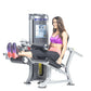 Woman in purple sports bra and pink shorts using black and silver leg extension machine with weight stack on white background