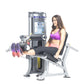 Woman using black and silver leg extension machine with purple sports bra and pink shorts on white background