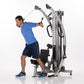 Man in blue shirt using silver and black functional trainer machine with cable handles on white background