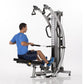 Man in blue shirt using silver and black functional trainer machine with dual cable system on white background