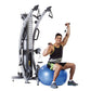 Man performing shoulder exercise on silver TuffStuff functional trainer with dual pulleys, seated on blue stability ball