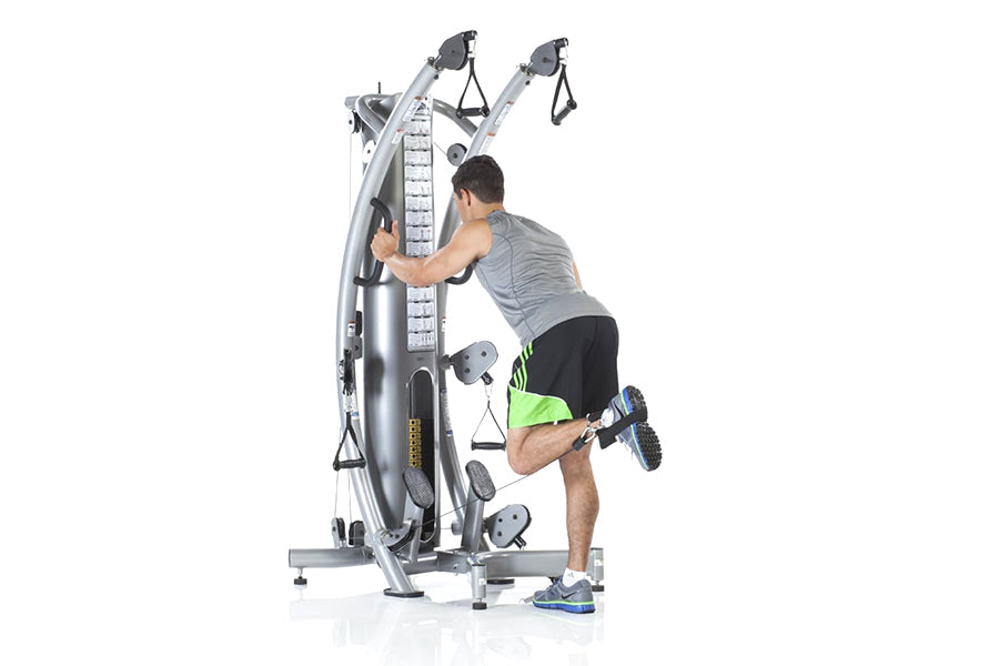 Man using silver TuffStuff six-pack functional trainer with dual cable machines and measurement scale, worn by model on white