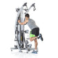 Man using silver multi-station functional trainer with dual cable pulleys and measurement scale, wearing gray shirt and black
