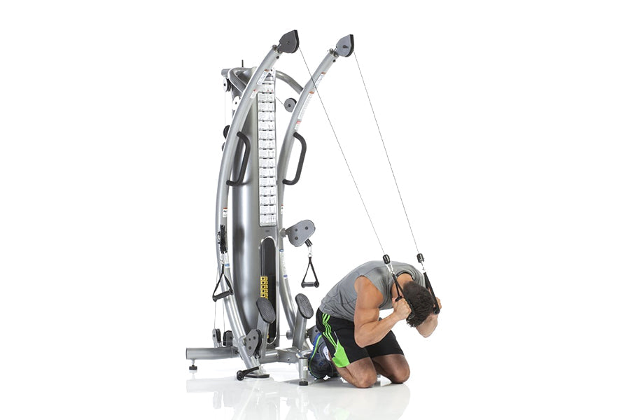 TuffStuff Six-Pak Base functional trainer with dual cable stations and height-adjustment column, shown with male model demons