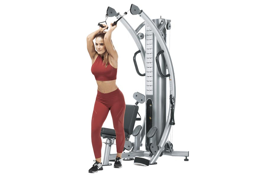 Woman in burgundy sports bra and leggings using silver and black functional trainer machine with dual cables and handles