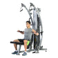 Man using gray and black functional trainer with dual cable systems and weight stack, seated position