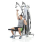 Man using silver and black dual cable functional trainer machine with pulleys and weight stack, on white background