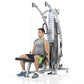 Man using gray and black dual-pulley functional trainer with measurement scale, seated on black bench in gym setting