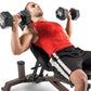 Man in red tank top performing dumbbell exercise on brown weight bench with 25-pound dumbbells