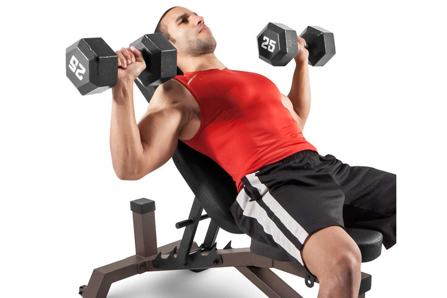Man in red tank top performing dumbbell exercise on brown weight bench with 25-pound dumbbells