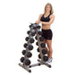 Woman wearing black sports bra and shorts standing next to vertical A-frame dumbbell rack with multiple pairs of hexagonal bl
