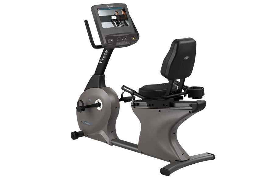 Gray and black recumbent exercise bike with digital display screen, black padded seat, and foot pedals on white background
