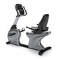 Gray and black commercial recumbent exercise bike with padded seat, handlebar display console, and footrest on white backgrou