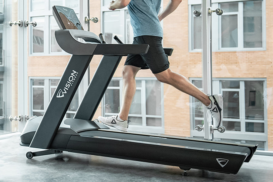 Man running on black Vision T600 treadmill with digital display in gym studio with windows