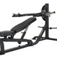 Black and gray weight bench with leg press attachment, barbell rack, and adjustable seat on white background